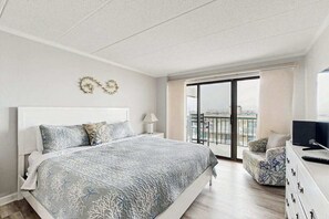 Ein Schlafzimmer mit Bett, Fernseher, Kommode und einem Balkon mit Blick.
