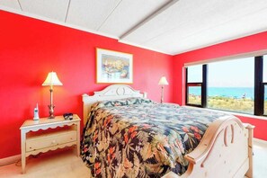A bedroom with a bed, two bedside tables, a window with a view, and a framed picture on the wall. - Oceanfront Mooring Condo w/ Ocean View, WiFi, W/D, AC - Relax and Unwind (Ocean City)