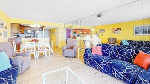 A living room with a sofa, chairs, a dining table, and a kitchen area. - Oceanfront Mooring Condo w/ Ocean View, WiFi, W/D, AC - Relax and Unwind (Ocean City)