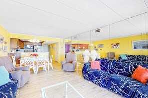 A living room with a sofa, chairs, a dining table, and a kitchen area. - Oceanfront Mooring Condo w/ Ocean View, WiFi, W/D, AC - Relax and Unwind (Ocean City)