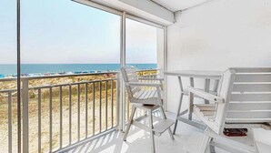 A balcony with a view of the beach, white chairs, and a table. - Oceanfront Mooring Condo w/ Ocean View, WiFi, W/D, AC - Relax and Unwind (Ocean City)