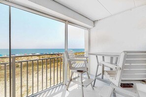 A balcony with a view of the beach, white chairs, and a table. - Oceanfront Mooring Condo w/ Ocean View, WiFi, W/D, AC - Relax and Unwind (Ocean City)