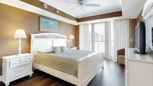 A bedroom with a bed, nightstands, a television, and a ceiling fan.