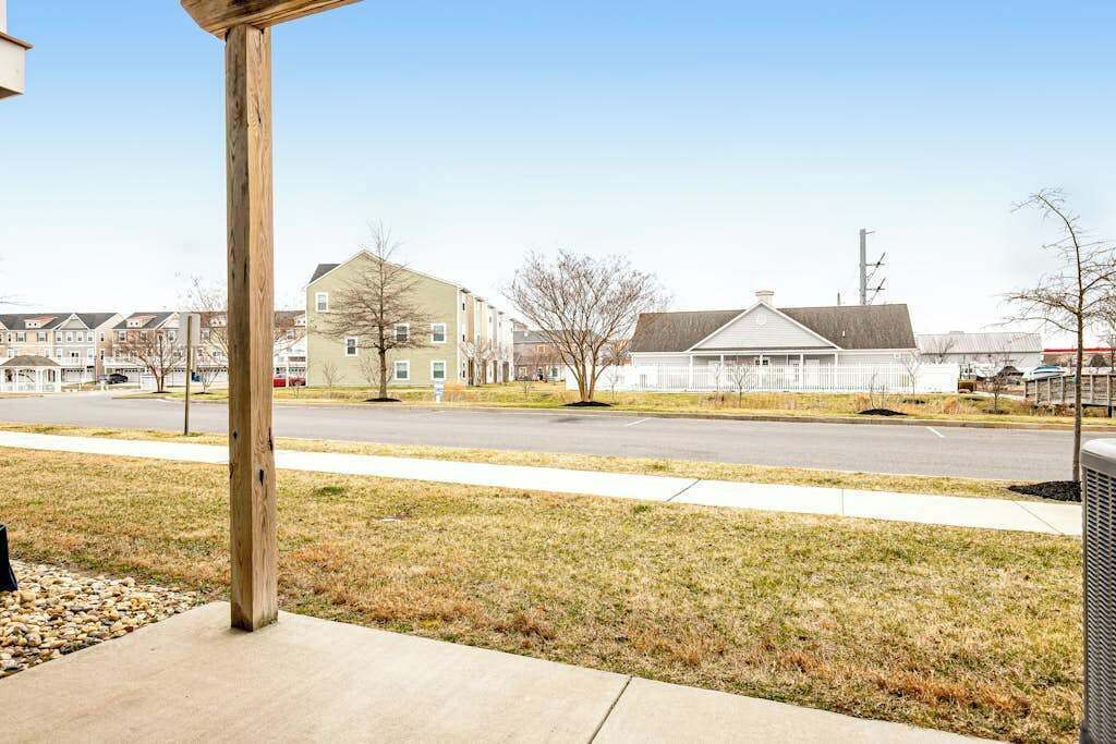 A residential street with houses, a sidewalk, and a wooden post.