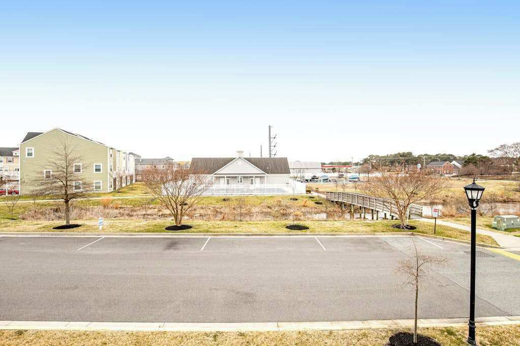 A parking lot with a building in the background, a lamp post, and a bridge.
