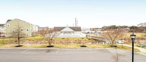 A parking lot with a building in the background, a lamp post, and a bridge.