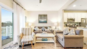 A living room with a sofa, armchair, coffee table, and a view of the outside. - Seaside Village - Bowline 13002-4 (West Ocean City)