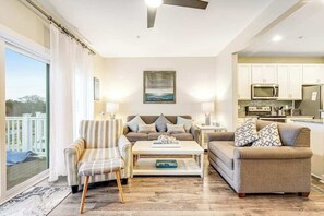 A living room with a sofa, armchair, coffee table, and a view of the outside. - Seaside Village - Bowline 13002-4 (West Ocean City)