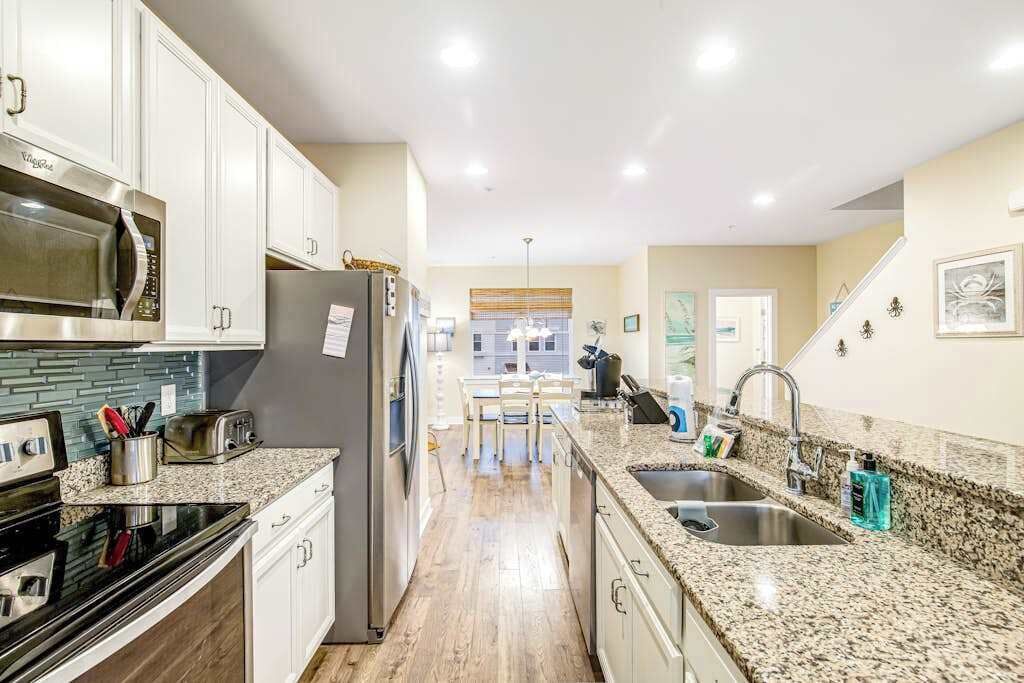 A kitchen with white cabinets, stainless steel appliances, granite countertops, and a central island.
