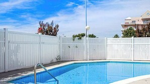 Ein Swimmingpool mit weißem Zaun, einer Metallleiter und einer Straßenlaterne.
