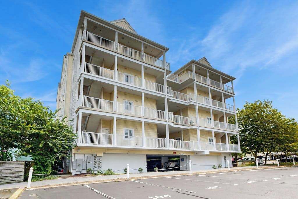Un hôtel à plusieurs étages doté de balcons, d’un parking et offrant une vue sur un ciel dégagé.