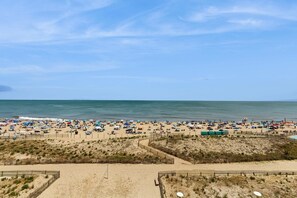 A beach with numerous umbrellas and people, sandy terrain, and a clear sky. - Gateway Grand 410 (Ocean City)