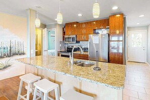A modern kitchen with granite countertops, stainless steel appliances, and wooden cabinets. - Oceanfront Happy House duplex with ocean view, WiFi, W/D, & direct beach access (Ocean City)