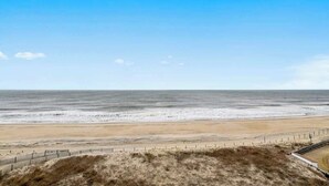 A beach with a fence and grassy area in the foreground. - Eastwinds 505 (Ocean City)