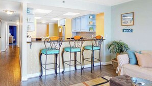 Uma sala de estar com espaço de bar, sofá, mesa de centro e planta em vaso.