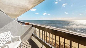 Varanda com vista para o oceano, uma cadeira branca e uma estrutura de concreto.