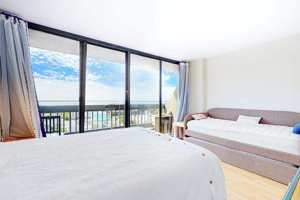 Habitación de hotel con una cama grande, un sofá, una mesita y un balcón con vistas.