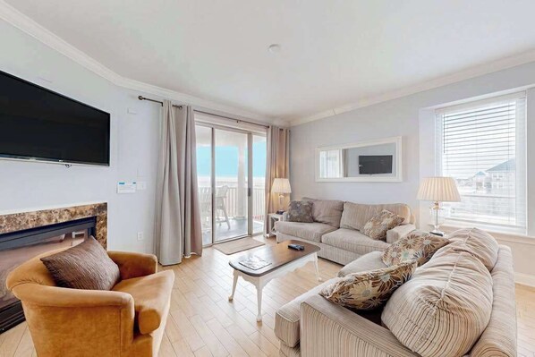 A living room with a sofa set, a coffee table, a TV, and a fireplace. - Belmont Towers 301 (Ocean City)