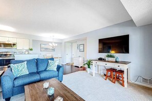 A modern living room with a sofa, coffee table, and a desk with stools. - Heron Haven (Ocean City)
