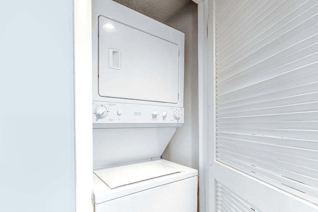 A laundry room with a stacked washer and dryer, a control panel, and a vented dryer.