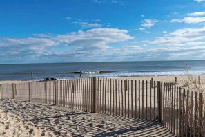A beach with a wooden fence, sandy beach, and ocean waves. - Spacious townhouse with ocean view, private beach area, pool access, W/D & AC (Ocean City)