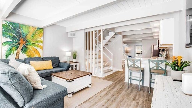 En moderne stue med en sofa, sofabord og et billede af en palme.