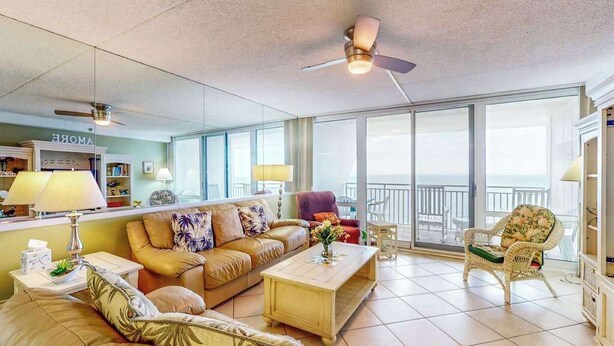 Ein geräumiges Wohnzimmer mit einer Couch, Sesseln, einem Couchtisch und einem Balkon mit Blick.