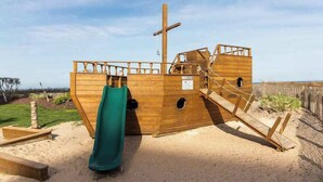 Eine hölzerne Piratenburg mit Rutsche, Treppe und Mast.