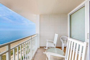 A balcony with a view of the sea, white wicker chairs, and a glass door. - Carousel 2105 (Ocean City)