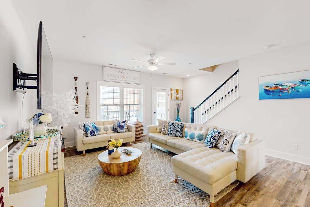 A spacious living room with a large sofa, a coffee table, and a staircase.
