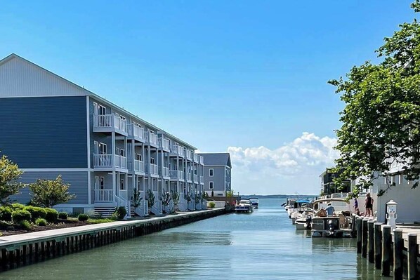 A waterfront hotel with multiple balconies, a dock, and boats. - Upscale canal-front townhome with pool, beach access, dock, balconies, & desks (Ocean City)