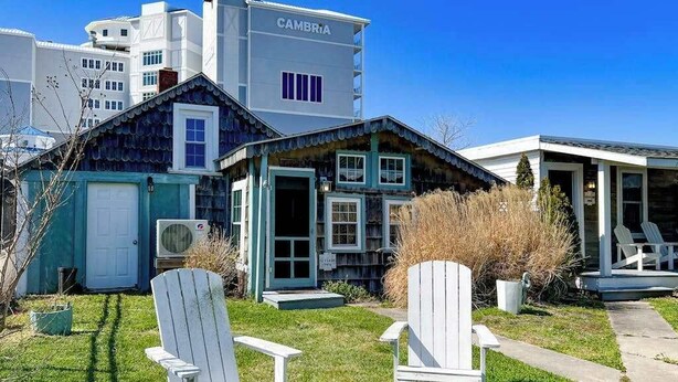 A house with a garage, a porch, and two Adirondack chairs in the yard. - Cottages on St Louis #2 (Ocean City)