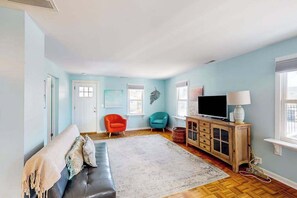 Ein Wohnzimmer mit einer Couch, zwei Sesseln, einem Fernseher und einem Schrank.