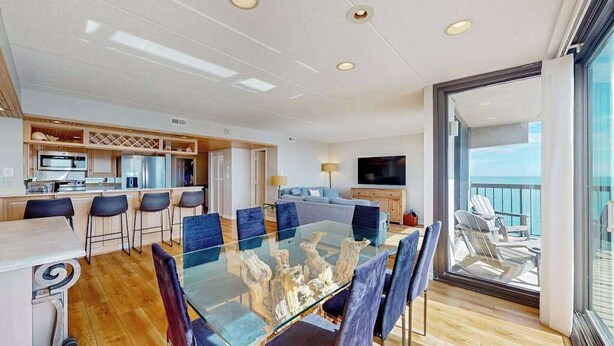 Een moderne keuken met een eethoek, een televisie en een balkon met stoelen.