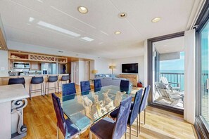 Een moderne keuken met een eethoek, een televisie en een balkon met stoelen.