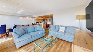 Een moderne woonkamer met twee banken, een glazen salontafel en een houten bijzettafeltje.