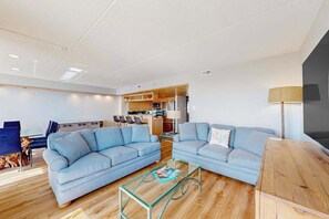 Ein modernes Wohnzimmer mit zwei Sofas, einem Glastisch und einem Holztisch.