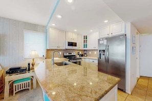 A modern kitchen with granite countertops, stainless steel appliances, and white cabinetry. - Fountainhead Towers 1001 (Ocean City)