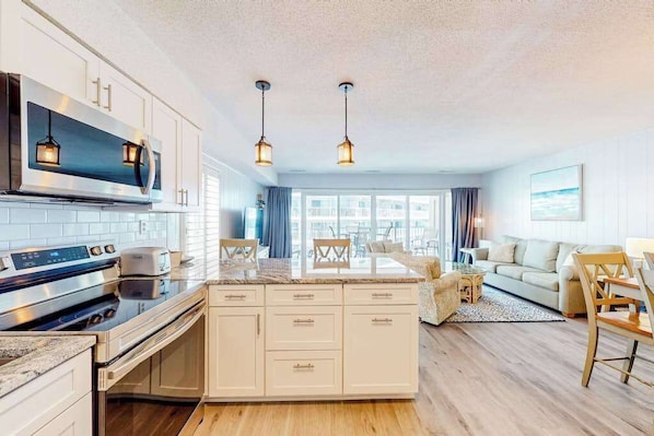 A modern kitchen with a central island, built-in oven, and stainless steel appliances. - Ultimate beach getaway with ocean view, open layout, garage parking, & streaming (Ocean City)