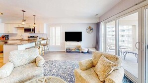 Un soggiorno moderno con divano, tavolino, televisore e un balcone con mobili da esterno.
