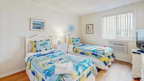 Habitación con dos camas, un televisor y una ventana con persianas.