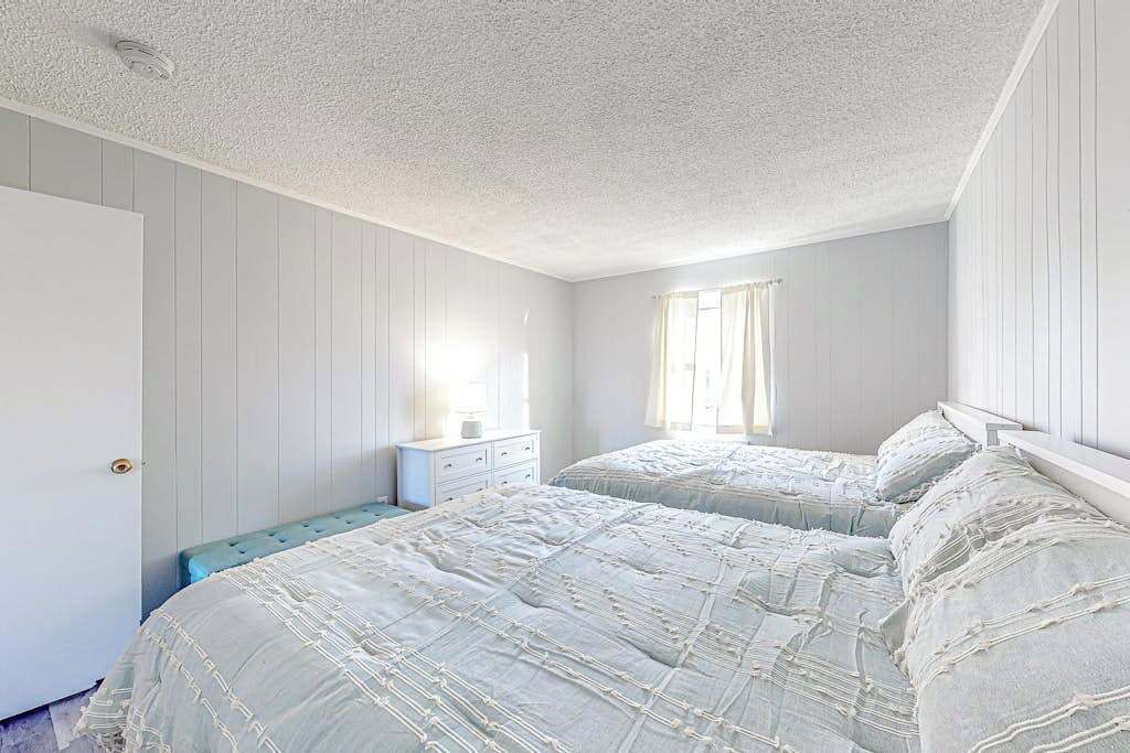 Ein Schlafzimmer mit zwei Betten, einem Schminktisch und einem Fenster mit Vorhängen.