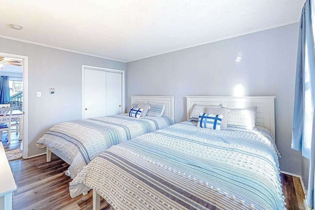 Un dormitorio con dos camas, una puerta y vistas al exterior.