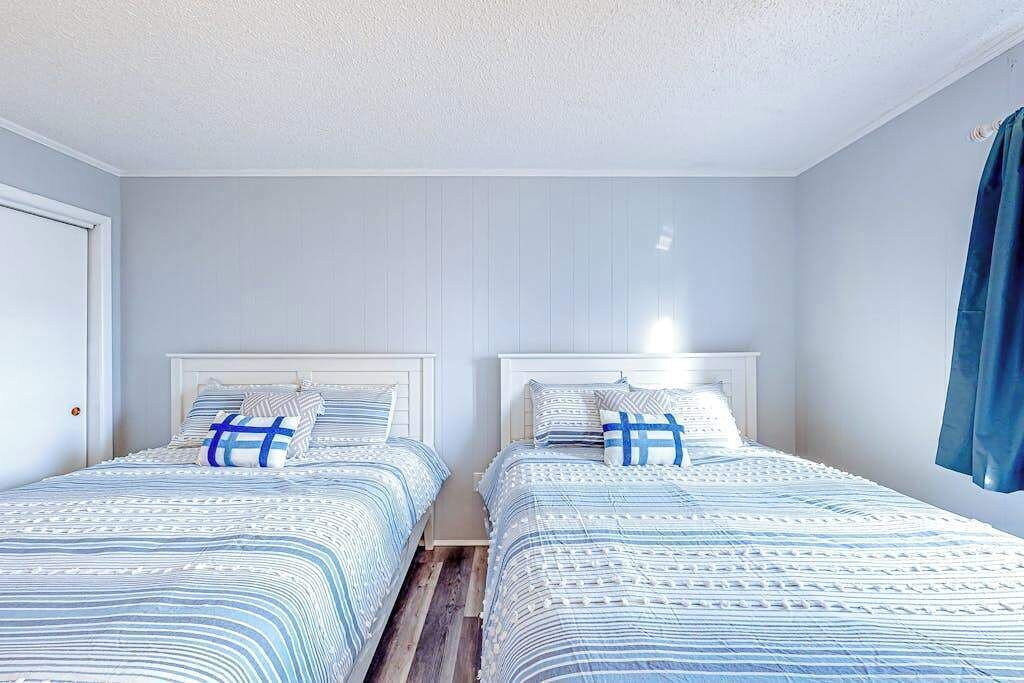 A twin room with two beds, white headboards, and a blue curtain.