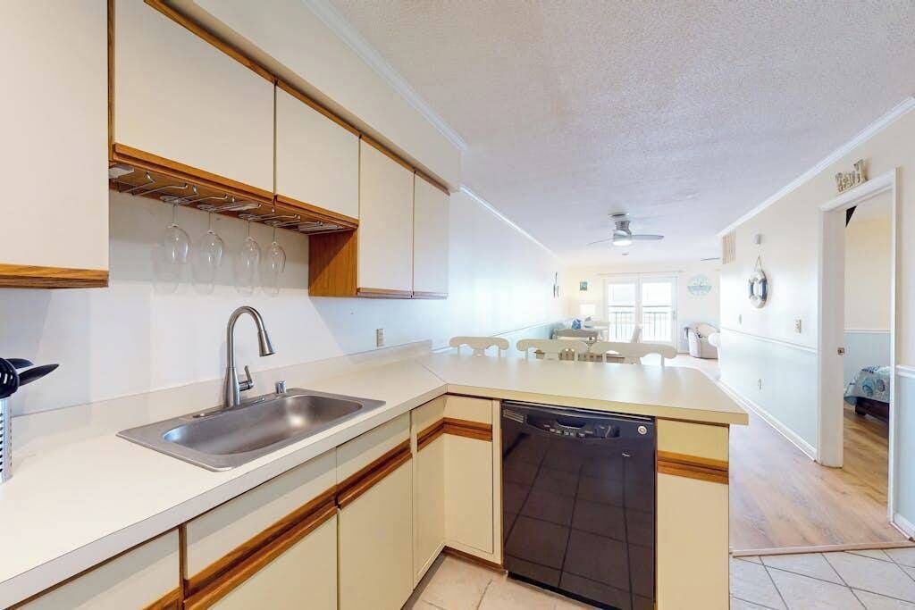 Una cocina moderna con lavavajillas, un fregadero y copas de vino en un expositor.