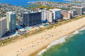 A coastal hotel with multiple high-rise buildings, a beach, and a pool area. - 15th-floor oceanfront condo with pool, central AC & beach access (Ocean City)