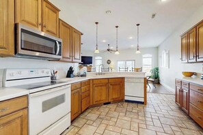 A kitchen with wooden cabinets, a microwave, stove, and a dishwasher. - Heron Harbour Retreat 302 Gull Ct (Ocean City)