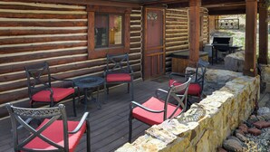Een vakantiehuisje van hout met een terras, buitenzitplaatsen en een barbecue.