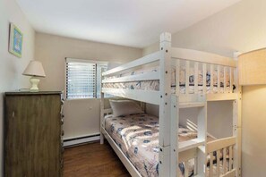 Une chambre avec un lit superposé, une fenêtre, une lampe et un placard.