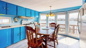 Una cocina con armarios azules, una mesa de comedor con sillas, una estufa y un refrigerador.